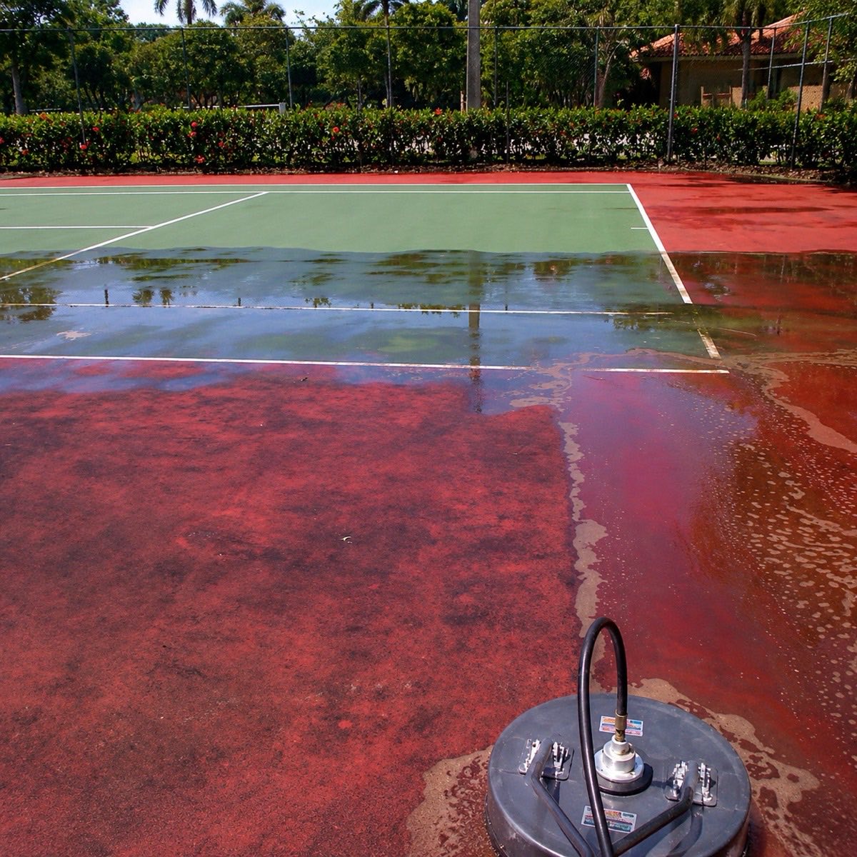 Sport court half cleaned by pressure washing, showing the before-and-after line