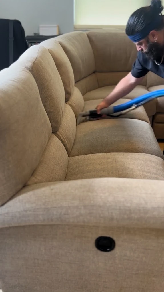 Technician steam cleaning a beige fabric sectional